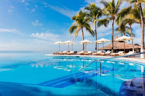 a swimming pool with umbrellas and the ocean at Krystal Grand Nuevo Vallarta in Nuevo Vallarta 