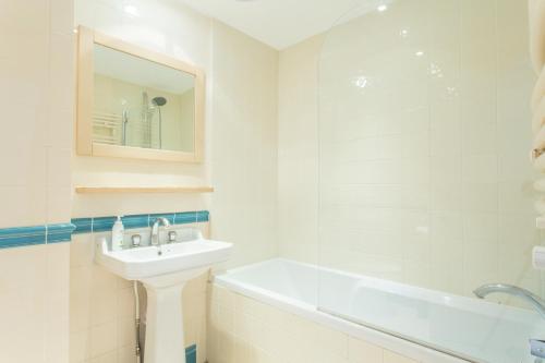 La salle de bains blanche est pourvue d'un lavabo et d'une baignoire. dans l'établissement The Harrods Mews - Modern 4BDR + Rooftop & Garage, à Londres