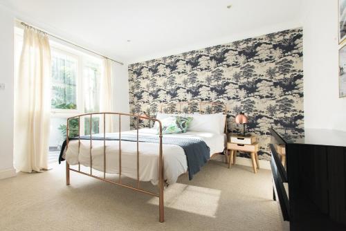 a bedroom with a bed with a black and white wallpaper at The Harrods Mews - Modern 4BDR + Rooftop & Garage in London