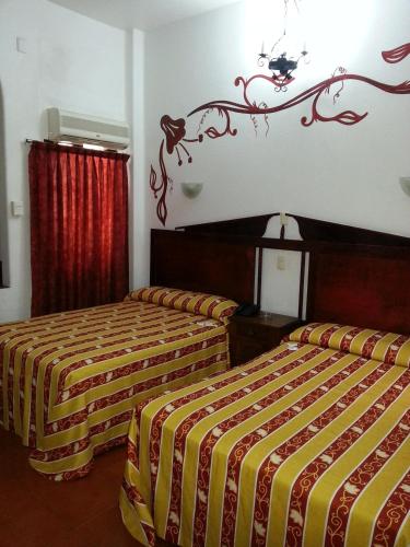 a hotel room with two beds with yellow and red sheets at Hotel Colonial in Manzanillo