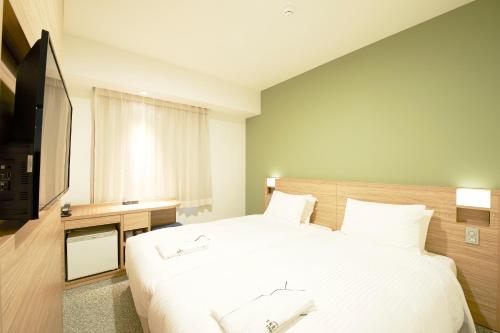 東京的住宿－東京金沙町酒店，卧室配有一张白色大床和电视。