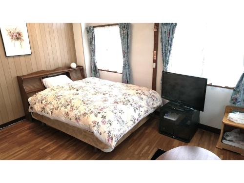 a bedroom with a bed and a flat screen tv at Hitoyoshi Morinohall Ladies in - Female Only in Hitoyoshi