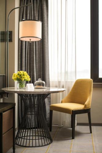 a table and a yellow chair and a lamp at Artyzen Grand Lapa Macau in Macau