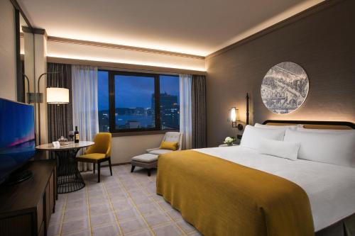 a hotel room with a bed and a desk and a television at Artyzen Grand Lapa Macau in Macau