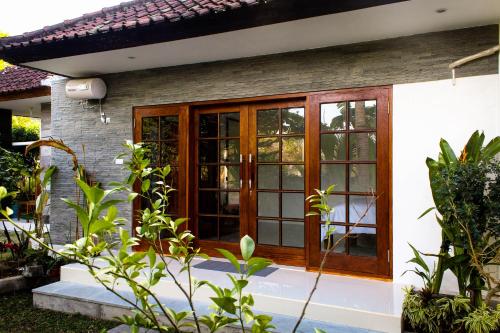 une maison avec des portes et des fenêtres en bois dans l'établissement Pier26 Bali Homestay, à Nusa Dua