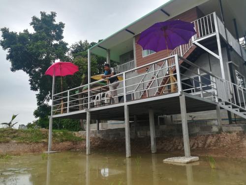a flooded house with people sitting on a balcony with umbrellas at BN Resort in Ban Nong Chum Saeng