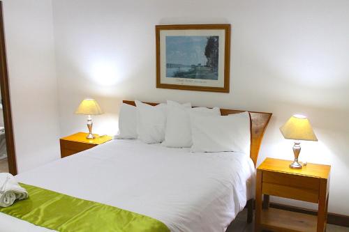 a bedroom with a large white bed with two lamps at Apartamentos Reforma in Guatemala