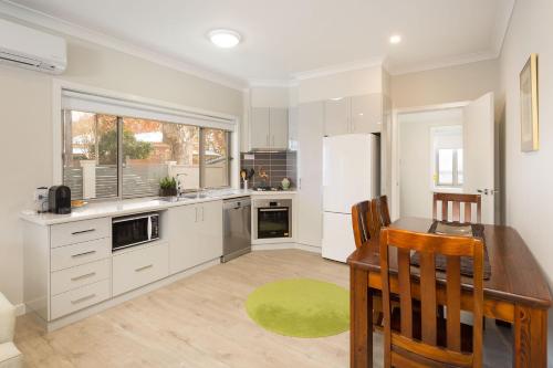 a kitchen with a table and a refrigerator at Central Sojourn on Wilcox in Albury