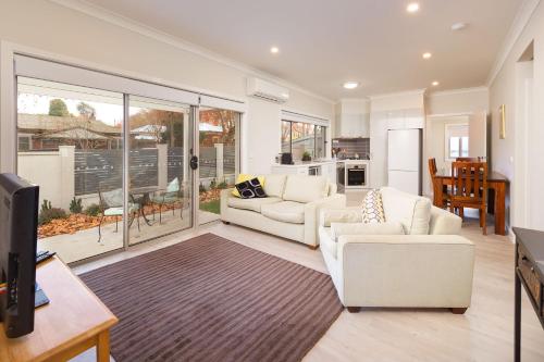 a living room with two white couches and a tv at Central Sojourn on Wilcox in Albury