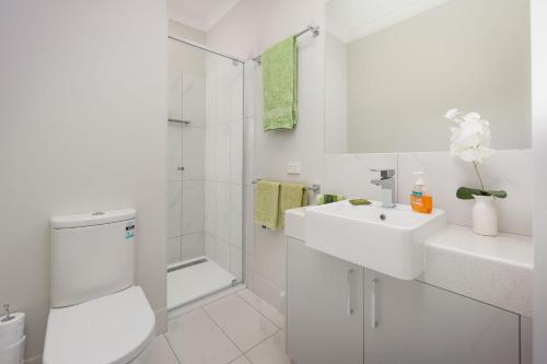a white bathroom with a toilet and a sink at Central Sojourn on Wilcox in Albury