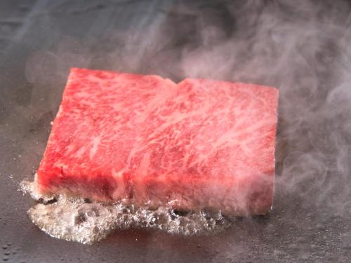 a piece of meat on a table with smoke at Garden Terrace Saga Hotel & Resorts in Saga