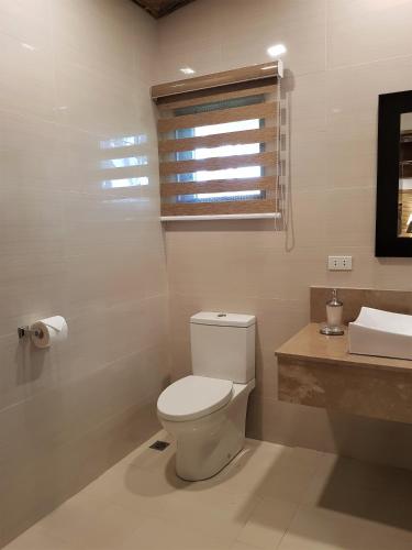 a bathroom with a toilet and a sink and a window at Casitas de Victoria in Nasugbu