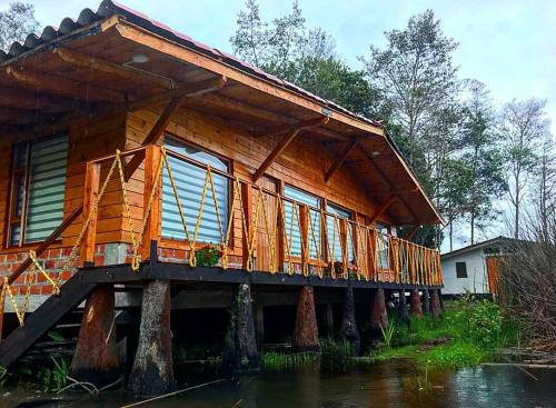 a wooden house on some logs in the water at Hermosa Cabaña en La Cocha-Finca INDIANA in El Encano