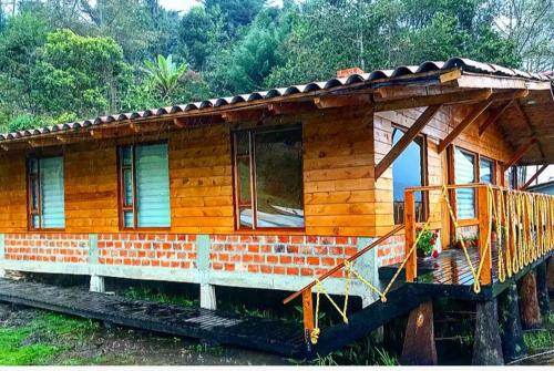 a small wooden house with a porch on at Hermosa Cabaña en La Cocha-Finca INDIANA in El Encano