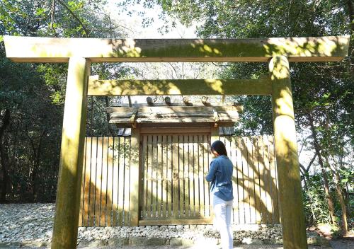 a woman standing in front of a wooden gate at Ryoso Uminocho in Ise