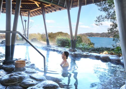 a woman in a swimming pool next to the water at Ryoso Uminocho in Ise