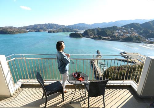 a person standing on a balcony looking at the water at Ryoso Uminocho in Ise