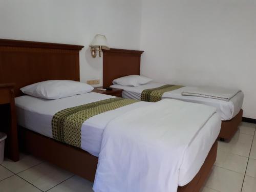 a hotel room with two beds with white sheets at Semeru Park Hotel in Pasuruan