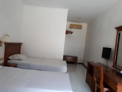 a hotel room with two beds and a television at Semeru Park Hotel in Pasuruan