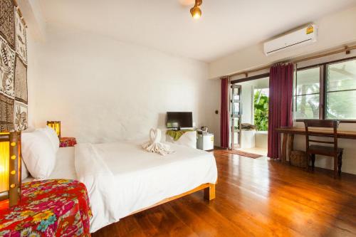a bedroom with a white bed and a living room at Koh Mak Cococape Resort in Ko Mak