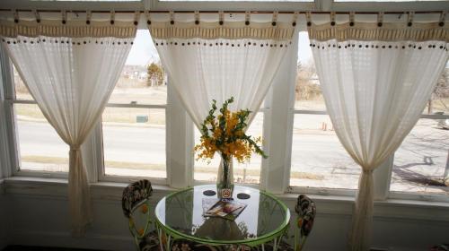 a vase of flowers on a table in front of a window at A Night to Remember B & B in Niagara Falls