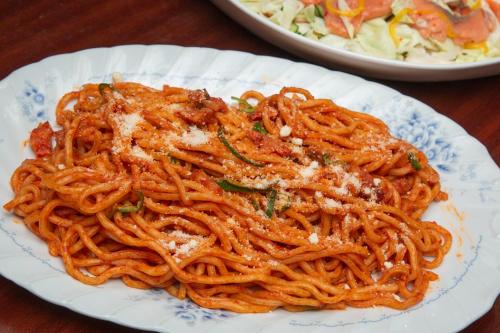 a plate of spaghetti on a table with a salad at Kuretake Inn Gotemba Inter Gold Cabin in Gotemba