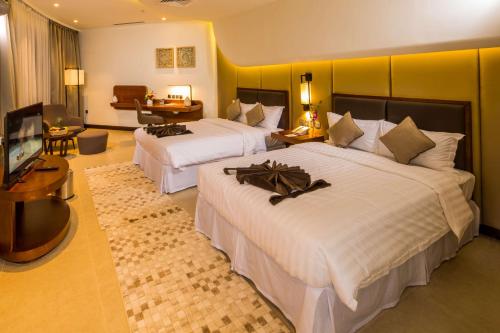 a hotel room with two beds and a television at Arch Hotel in Manama