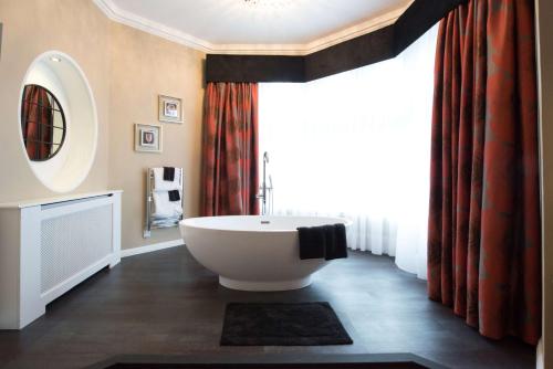 a bathroom with a tub and a large window at Burlington Hotel, BW Premier Collection by Best Western in Folkestone