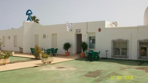 a white building with green tables and chairs at Virgen del Mar Holidays in Mojácar