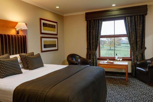 a hotel room with a large bed and a window at Best Western Garfield House Hotel in Chryston