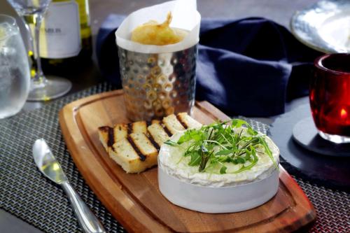 a wooden cutting board with food on a table at Best Western Plus Dunfermline Crossford Keavil House Hotel in Dunfermline