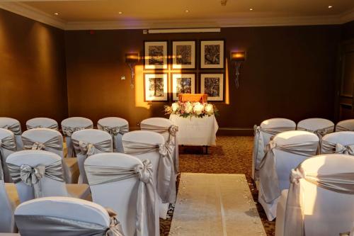 a room with rows of chairs and a table with flowers at Best Western Garfield House Hotel in Chryston
