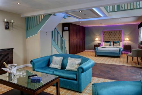 a living room with a blue couch and a bed at Rogerthorpe Manor Hotel in Pontefract