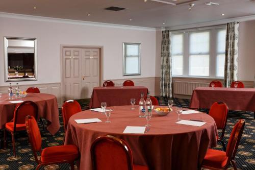 a conference room with tables and chairs with red table cloth at Best Western Balgeddie House Hotel in Glenrothes