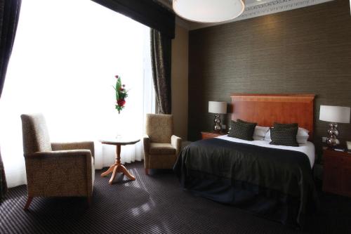 a hotel room with a bed and a chair at Best Western Garfield House Hotel in Chryston