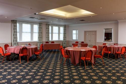 a dining room with tables and red chairs at Best Western Balgeddie House Hotel in Glenrothes