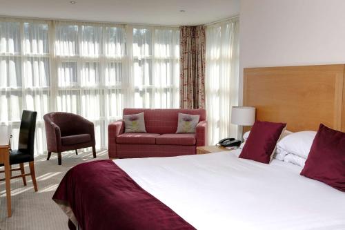a hotel room with a large bed and a chair at Best Western Balgeddie House Hotel in Glenrothes