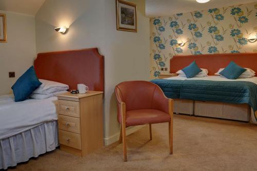 a bedroom with two beds and a chair and a dresser at Woodlands Hotel, BW Signature Collection in Dundee