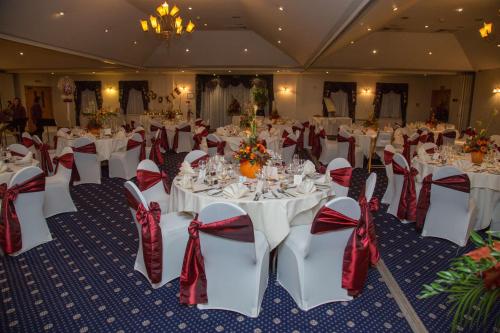 a banquet hall with white tables and red bows at Best Western Plus Bentley Hotel in Lincoln