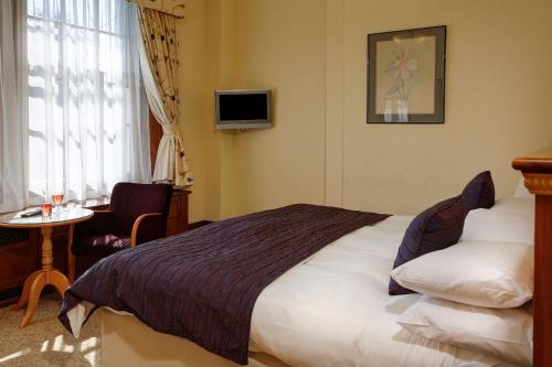 a hotel room with a bed and a table and a tv at Best Western Balgeddie House Hotel in Glenrothes