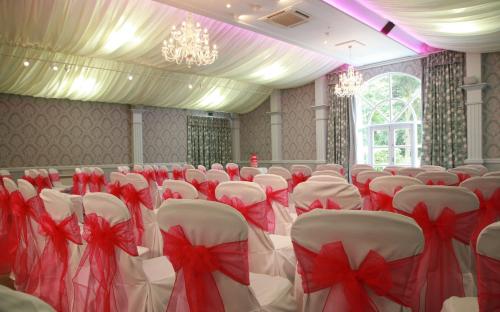 a room filled with white chairs with red bows at Best Western Plus Dunfermline Crossford Keavil House Hotel in Dunfermline
