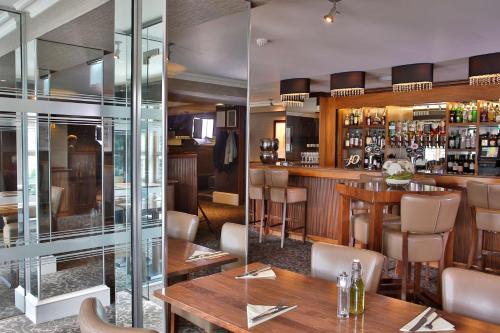 a restaurant with a bar with wooden tables and chairs at Best Western Motherwell Centre Moorings Hotel in Motherwell