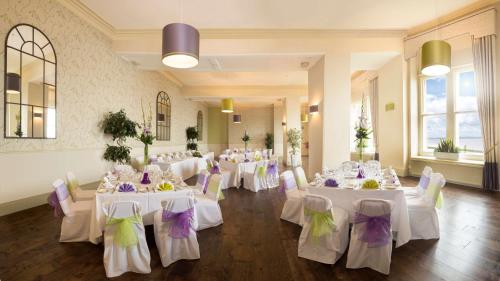 a room with white tables and chairs with purple and green bows at Best Western Walton Park Hotel in Clevedon