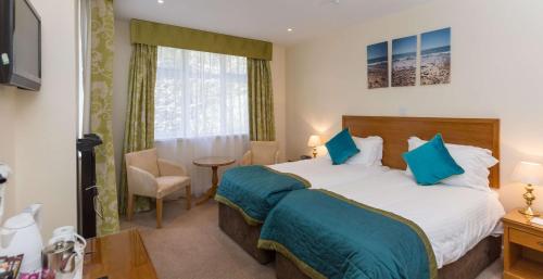 a bedroom with a large bed with blue pillows at Best Western Moores Central Hotel in St Peter Port