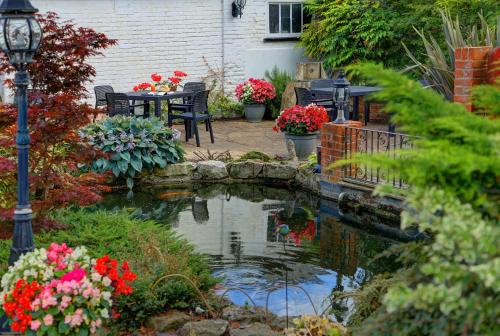 a garden with a pond with flowers and a street light at Best Western Annesley House Hotel in Norwich