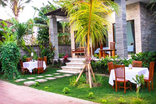 a patio with a table and chairs and a palm tree at Pier26 Bali Homestay in Nusa Dua