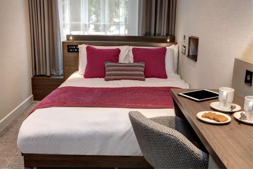 a bedroom with a large bed with pink pillows at Best Western Plus Delmere Hotel in London