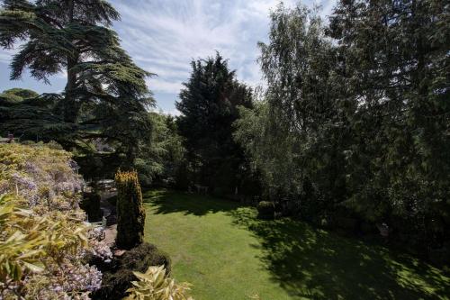 a garden with trees and green grass and bushes at The Grange at Oborne in Sherborne