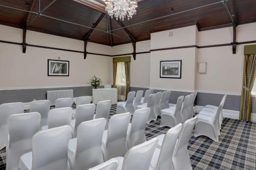 a room with white chairs and a chandelier at Burn Hall Hotel in Huby