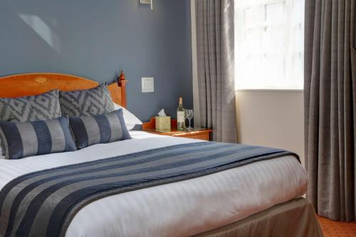a bedroom with a bed with blue walls and a window at Best Western Sysonby Knoll Hotel in Melton Mowbray